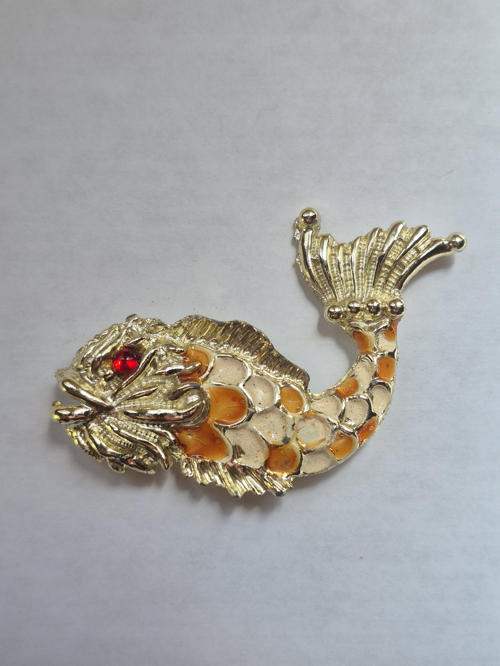 Vintage gold-tone enamel fish brooch featuring textured red rhinestone eye
